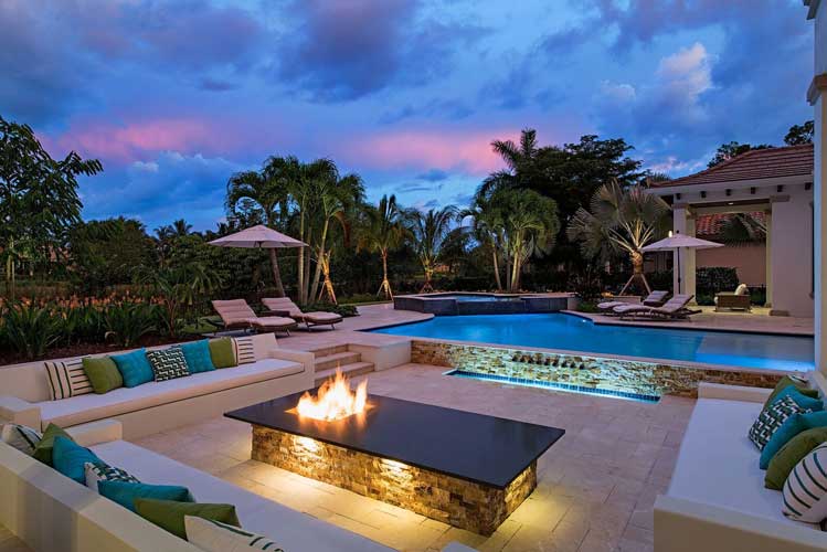 Night time view of a pool with sunken seating and firepit at an Estate lot in Estuary - Naples, Florida
