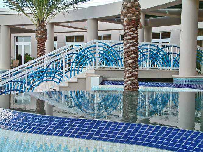 Esperia condo pool deck sits 4' below the building which allowed for an undulating water wall with a bridge crossing. - Bonita Springs, Florida
